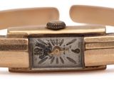 a gold wrist watch with a square face on it