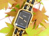 an image of a black and gold watch sitting on top of a pile of leaves