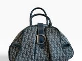 un sac à main bleu et noir posé sur une surface blanche
