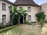 une photo d'un bâtiment en pierre avec un jardin devant
