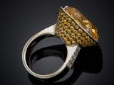 a yellow sapphire and diamond ring on a black surface