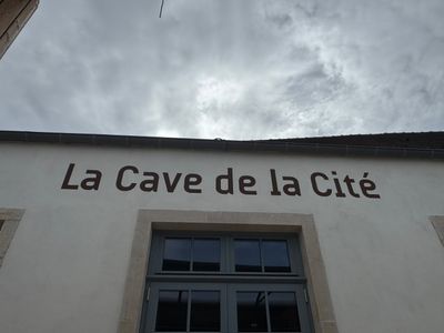 une enseigne sur le mur d'un immeuble indiquant « La Cave de la Cité »