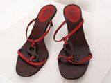pair of brown and red sandals with red straps on a white surface