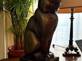 a statue of a cat sitting on a desk next to a lamp