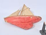 a red boat that is sitting on top of a black stand
