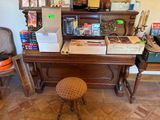 un piano et un tabouret dans une pièce où se trouvent de nombreux cartons