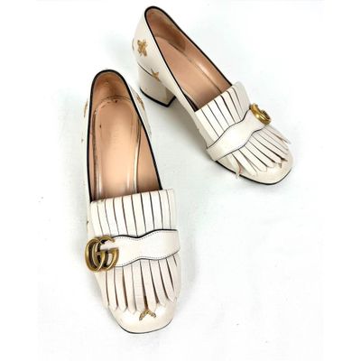 une paire de chaussures blanches ornées d'une boucle dorée
