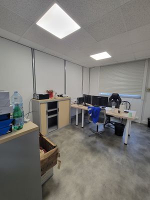 une salle où se trouvent de nombreux bureaux et chaises