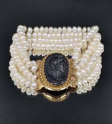 un gros plan sur un bracelet orné de perles et d'une pièce romaine