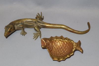a gold lizard and a gold fish on a white surface