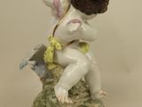 two porcelain figurines of cherensils and a bird on a pedestal