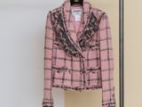 a pink jacket hanging on a clothes rack in front of a white wall