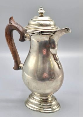 a silver coffee pot with a wooden handle sitting on top of a table