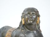 a bronze statue of a woman laying down on the ground