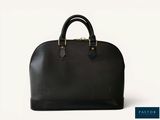 un sac à main noir avec une poignée dorée sur fond blanc
