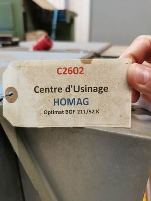 une personne tenant une étiquette sur laquelle est inscrit « homag »