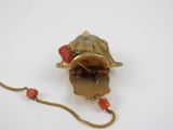 an image of a gold colored object with a red bead on it