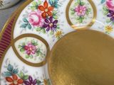 a plate with a gold plate on it next to a cup and saucer