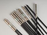 six black and gold chopsticks sitting next to each other on a white surface