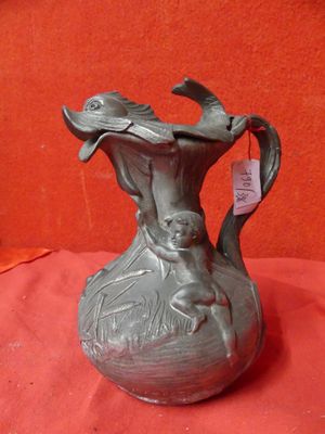 a metal vase with a bird on it on a red cloth