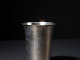 a silver cup sitting on a table with a black background