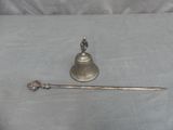 a silver bell and a spoon sitting on a table