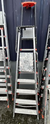 several metal ladders are stacked up against a blue wall