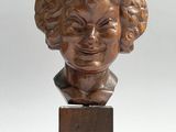 a bronze bust of a woman with curly hair on a wooden base