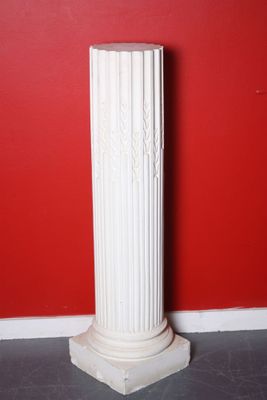 a white column with a red wall in the background