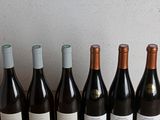 six bottles of wine are lined up on a wooden table
