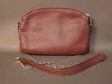 brown leather purse with gold chain strap sitting on a gray surface