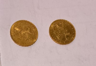 two gold coins sitting next to each other on top of a piece of paper