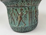 a green vase with a design on it on a white surface