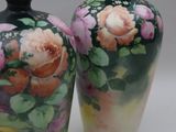 two vases with flowers painted on them sitting on a table