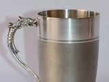 a silver cup with a dragon handle on it