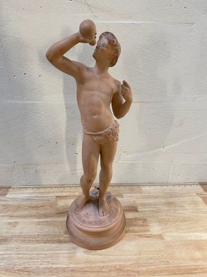 statue représentant un garçon en train de boire de l'eau à la bouteille, posée sur une table en bois
