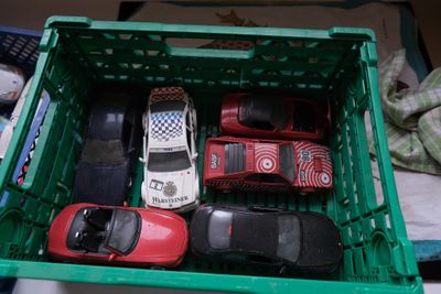 de nombreuses petites voitures dans une caisse verte posée sur un lit