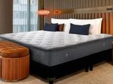 a bed with a mattress and a foot stool in a room