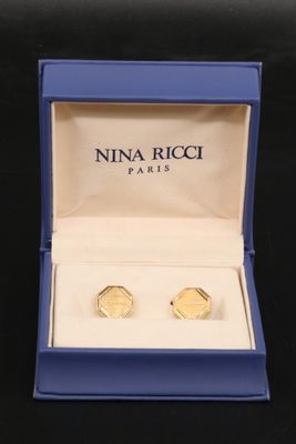 two pairs of gold cuff earrings in a blue box on a black surface