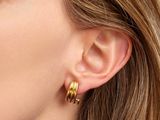 a close up of a woman wearing a pair of gold hoop earrings
