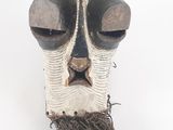 une image représentant un masque en bois orné d'une longue barbe, sur fond blanc