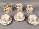 five cups and saucers and a teapot on the table