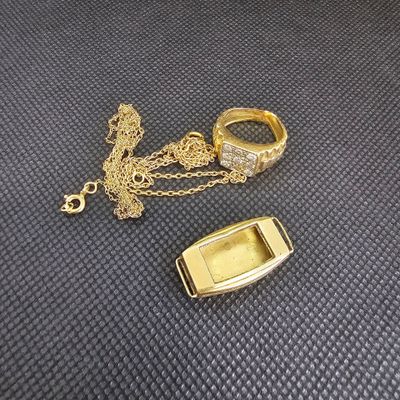 deux bagues et un collier posés sur une surface noire, avec une chaîne