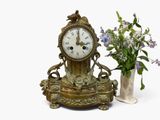 a clock sitting next to a vase with flowers in it