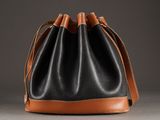 a black and tan leather bucket bag with a brown strap