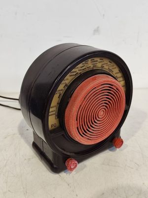 une radio noire et rouge posée sur une surface blanche
