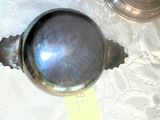 un objet en argent posé sur la table, à côté d'une coupe en argent