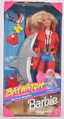 La poupée Barbie porte une veste rouge et un jean bleu.