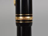 a close up of a pen with a gold band on it