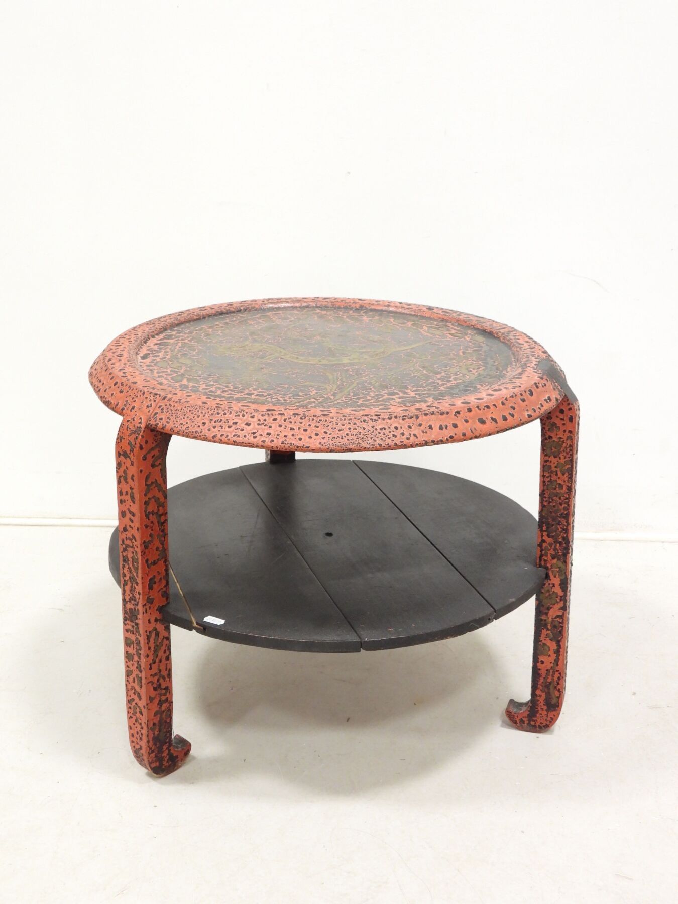 Table basse de forme circulaire en bois laqué dans les tons rouge et noir. Plateau orné d'un décor de dragon doré par...